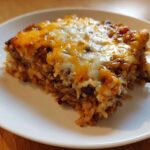 A close-up of a hearty slice of Black Bean and Rice Bake topped with melted cheddar and Monterey Jack cheese.