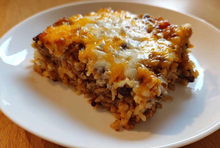 A close-up of a hearty slice of Black Bean and Rice Bake topped with melted cheddar and Monterey Jack cheese.