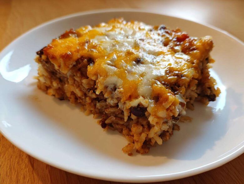 A close-up of a hearty slice of Black Bean and Rice Bake topped with melted cheddar and Monterey Jack cheese.