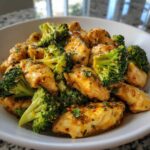 Close-up of tender pieces of Garlic Butter Chicken and Broccoli florets coated in a glossy, savory sauce.