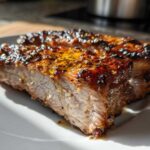 Close-up of a juicy, thick slice of Honey Garlic Pork with a caramelized, glistening glaze and sesame seeds.
