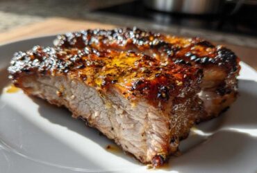 Close-up of a juicy, thick slice of Honey Garlic Pork with a caramelized, glistening glaze and sesame seeds.