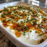 A close-up of the finished Hot Honey Ricotta Dip, topped with drizzled hot honey and fresh chives.