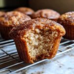 A close-up of a Rhubarb Muffin with Cinnamon Sugar Topping, showing a bite taken out to reveal the moist interior.