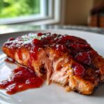 A close-up of a flaky cooked salmon fillet topped with a thick, glossy strawberry balsamic glaze.